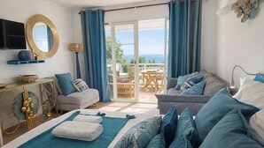 Ein Schlafzimmer mit Bett, einer Couch, einem Fernseher und einem Balkon mit Blick.