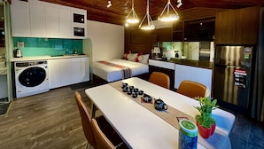 A compact hotel room with a kitchenette, a bed, a dining table with teapots, and a Sharp refrigerator. - Maison Mackeno (Hanoi)