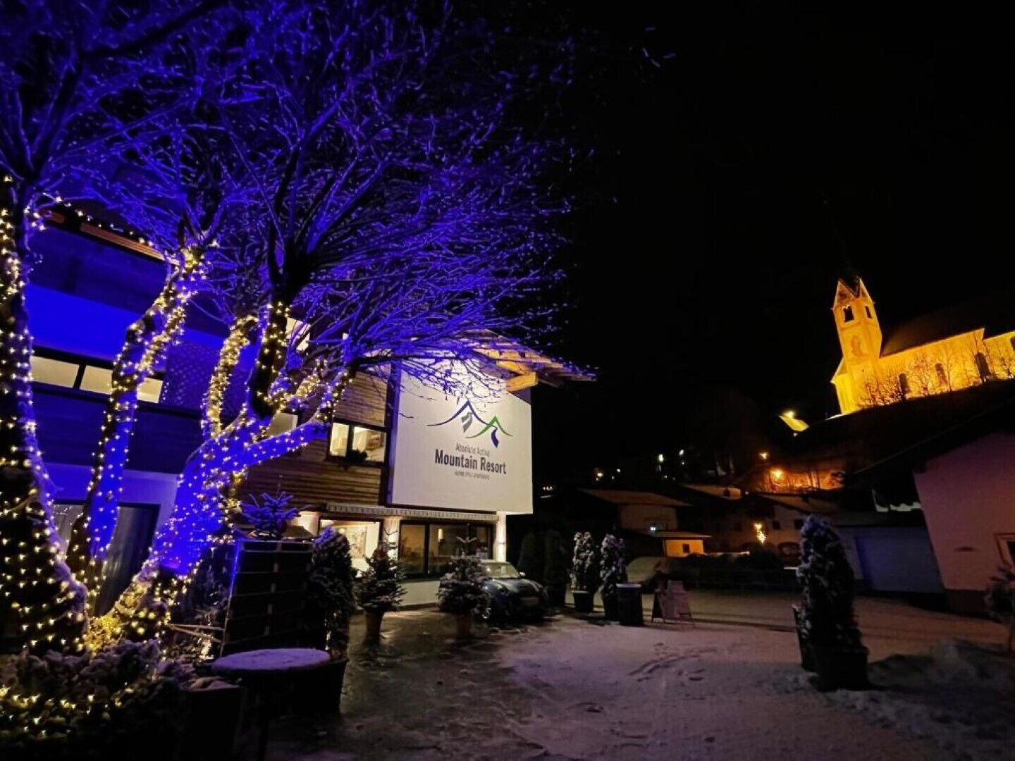 Ein Gebäude mit einem Schild für Mountain Resort, umgeben von Bäumen, die mit blauen Lichtern geschmückt sind.