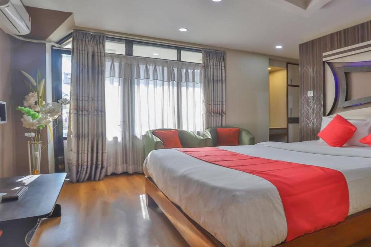 Een hotelkamer met een groot bed, een nachtkastje, een stoel en een bureau.