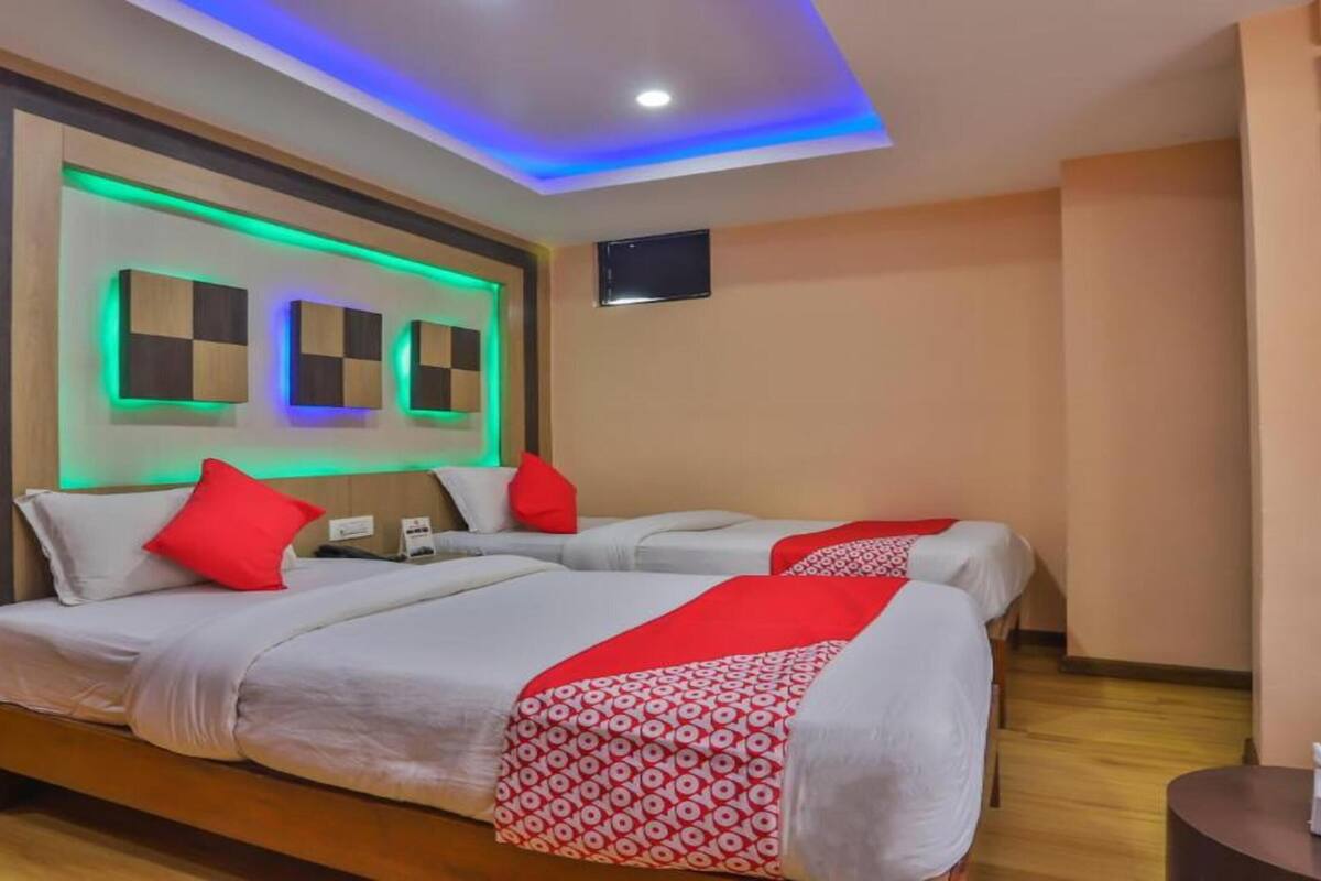 Een hotelkamer met twee bedden, een flatscreen-televisie en een plafond met LED-verlichting.