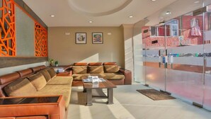 Un espace de détente moderne avec des canapés en cuir, une table basse et une cloison en verre dont l’intérieur est de couleur rose.