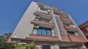 Un hôtel à plusieurs étages, avec une grande enseigne « HÔTEL » bien visible sur la façade, des balcons à chaque étage et un ciel dégagé en arrière-plan.
