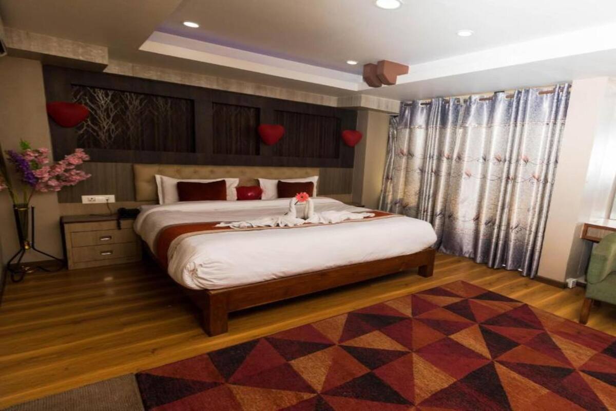 Een moderne hotelkamer met een groot bed, een groene bank en een houten vloer.