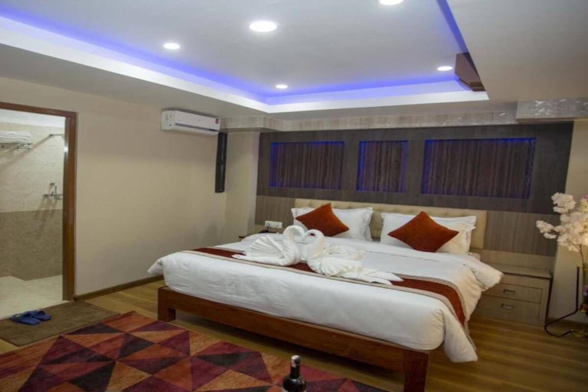 Een hotelkamer met een groot bed, een spiegel, een airconditioning en een kamerbreed tapijt met dessin.