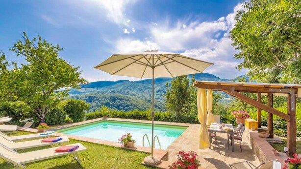 Un espace piscine équipé de chaises longues, d’un parasol et d’une table avec des chaises.