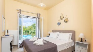 Ein Schlafzimmer mit Bett, Nachttischen, einem Schreibtisch und einem Balkon mit Pool.