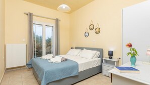 Ein Schlafzimmer mit Bett, Nachttisch, Lampe und Blick ins Freie.