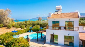 A modern two-story building with a pool, surrounded by greenery and overlooking a coastal landscape. - Blue Bay Villas Collection (Polis)