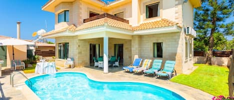 A two-story house with a swimming pool, outdoor seating, and a well-maintained garden.