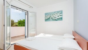 Un dormitorio con cama, un cuadro y un ventanal corredero que da a un espacio exterior.