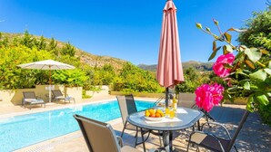 Ein Poolbereich mit Tisch, Stühlen und Sonnenschirmen.