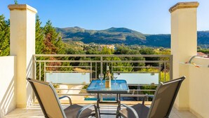 Ein Balkon mit Tisch und Stühlen mit Blick auf eine gebirgige Landschaft.
