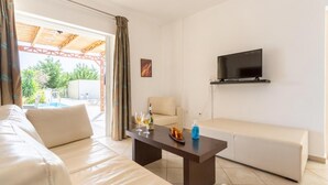 Een moderne woonkamer met een bank, een salontafel en een aan de muur bevestigde televisie.