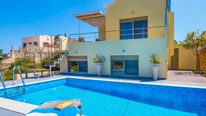 A modern two-story building with a swimming pool, outdoor seating, and potted plants. - Litsarda Villas in Apokoronos (Apokoronas)