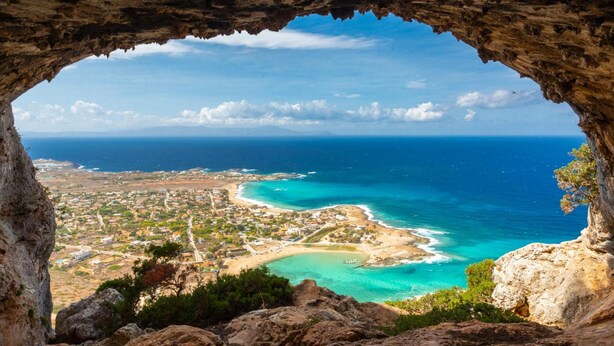 A coastal town viewed through a cave opening, with a clear view of the sea and a sandy beach. - Litsarda Villas in Apokoronos (Apokoronas)