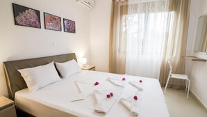 A neatly made bed with white linens and pink flowers, a bedside table with a lamp, and a chair. - Litsarda Villas in Apokoronos (Apokoronas)
