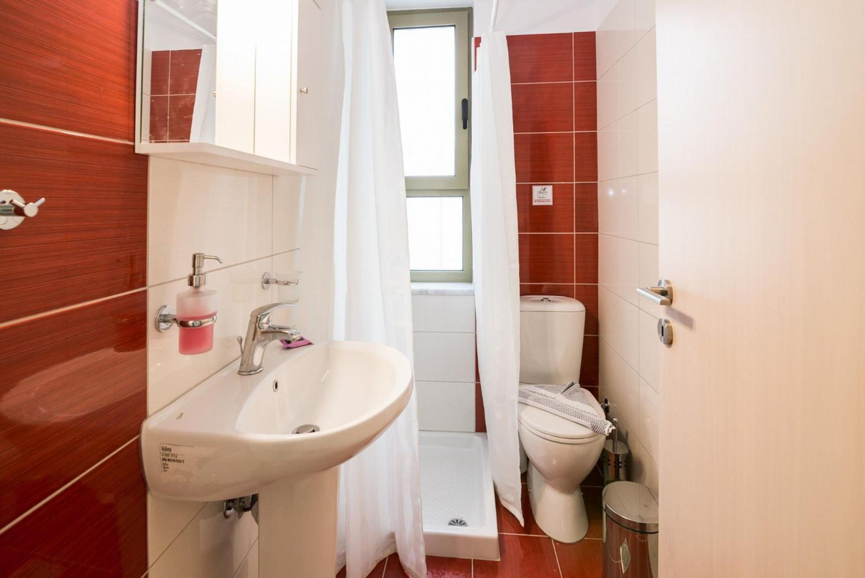 Une salle de bain avec un lavabo blanc, des toilettes et un espace douche.