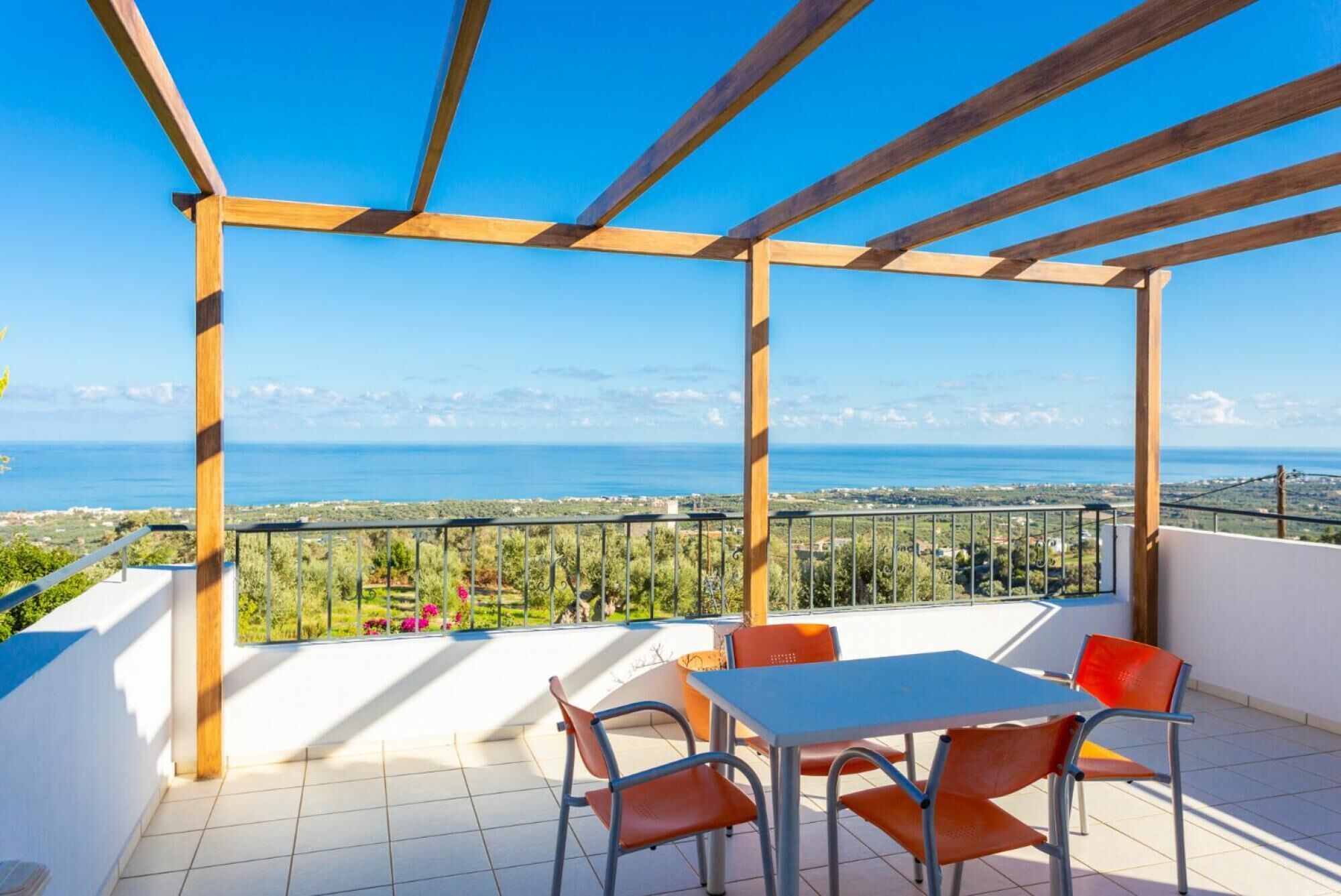 Un espacio al aire libre techado con una mesa y sillas, con vistas a un paisaje costero.