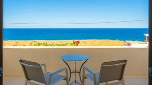 A balcony with two chairs and a small table, overlooking a beach with a clear view of the ocean. - Panormos Villas Collection (Mylopotamos)