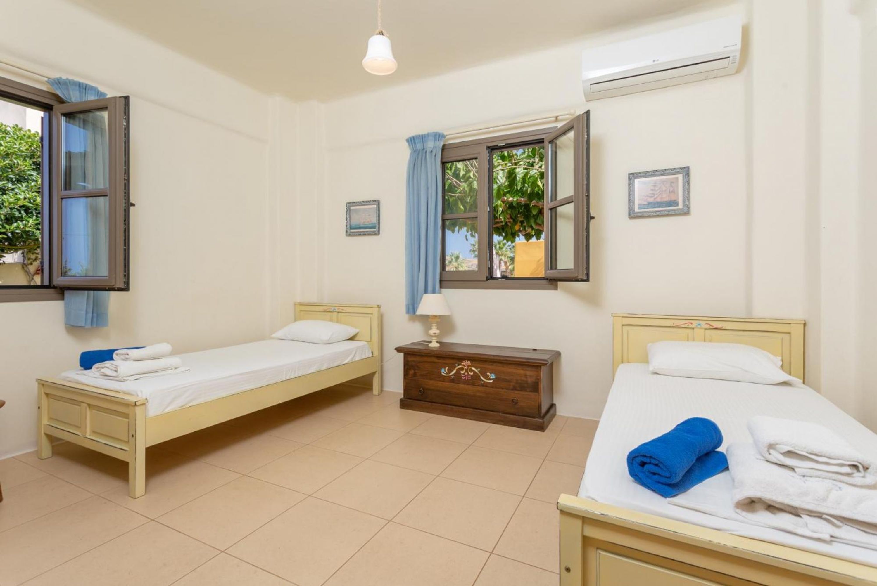 A room with two beds, a wooden dresser, and a window with curtains.