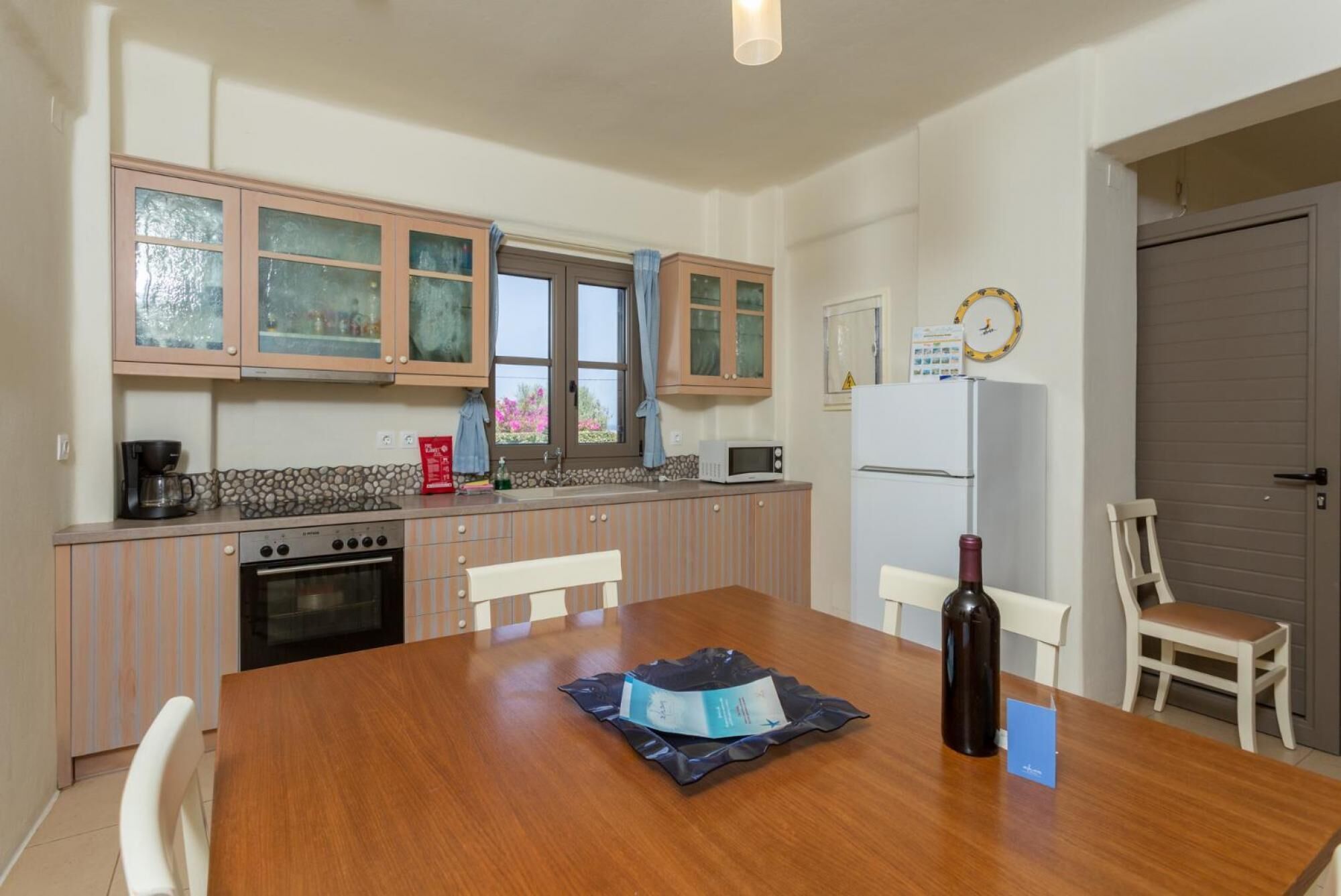 A compact kitchen with a wooden table, a refrigerator, a microwave, and a stove.