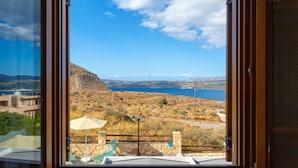 Un balcón con vistas a un paisaje costero, que incluye una masa de agua y montañas distantes.