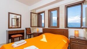 Een hotelkamer met een groot bed, twee nachtkastjes, een stoel, een bureau en een raam met uitzicht.