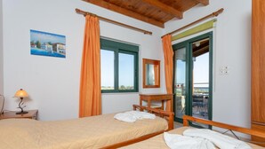 A bedroom with a bed, a desk, a chair, a window, and a balcony. - Spiros Villas Collection (Sfakia)