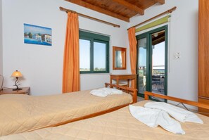 Un dormitorio con una cama, un escritorio, una silla, una ventana y un balcón.
