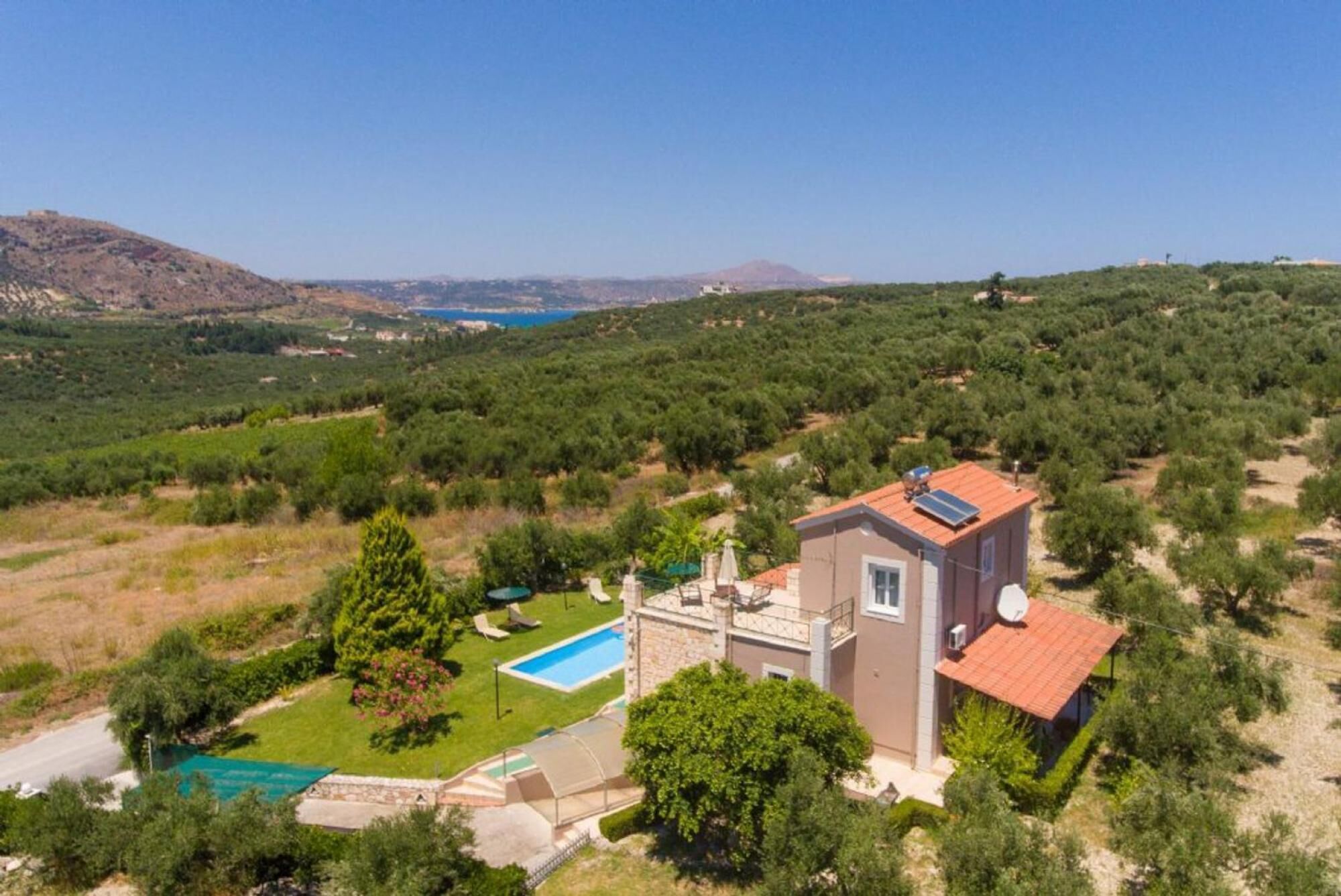 Une villa avec piscine, entourée d’oliviers et de montagnes.