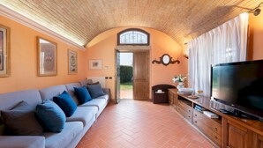 Ein gemütliches Wohnzimmer mit einer Couch, Fernseher und einem Essbereich mit Tisch und Stühlen.