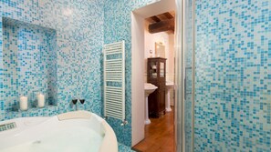 A bathroom with mosaic tile walls, a bathtub, a wooden cabinet, and a white sink.