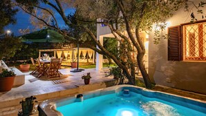 Un área junto a la piscina con un jacuzzi, mobiliario exterior y una zona de comedor.