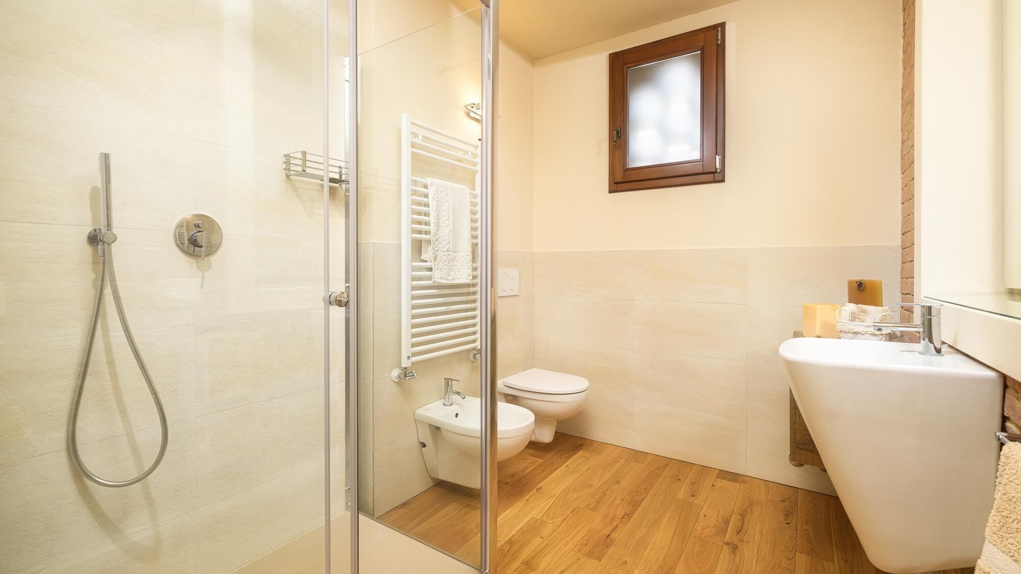 A bathroom with a glass shower enclosure, a toilet, and a sink with a mirror.