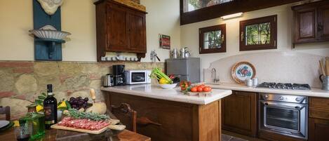 A kitchen with a stone backsplash, wooden cabinets, a built-in stove, and a dining area with a wooden table.