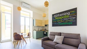 Een moderne woonkamer met een bank, eettafel, stoelen en een keuken op de achtergrond.