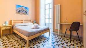Een slaapkamer met een bed, bureau, stoel, radiator en raam.
