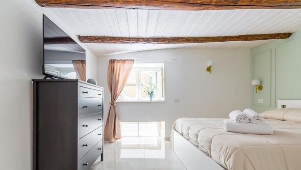 A bedroom with a bed, a dresser, a mirror, a window with curtains, and a light fixture. - Umberto s Nest at Toledo (Naples)