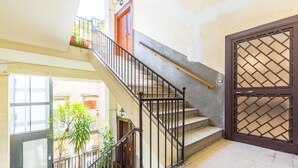 A staircase with a metal railing, a wooden door with a lattice design, and potted plants. - Umberto s Nest at Toledo (Naples)