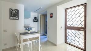 A dining area with a table and chairs, a microwave, and a small kitchen area. - Umberto s Nest at Toledo (Naples)