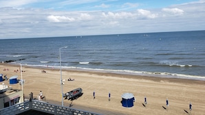 A beach with umbrellas, a lifeguard tower, and a boat.