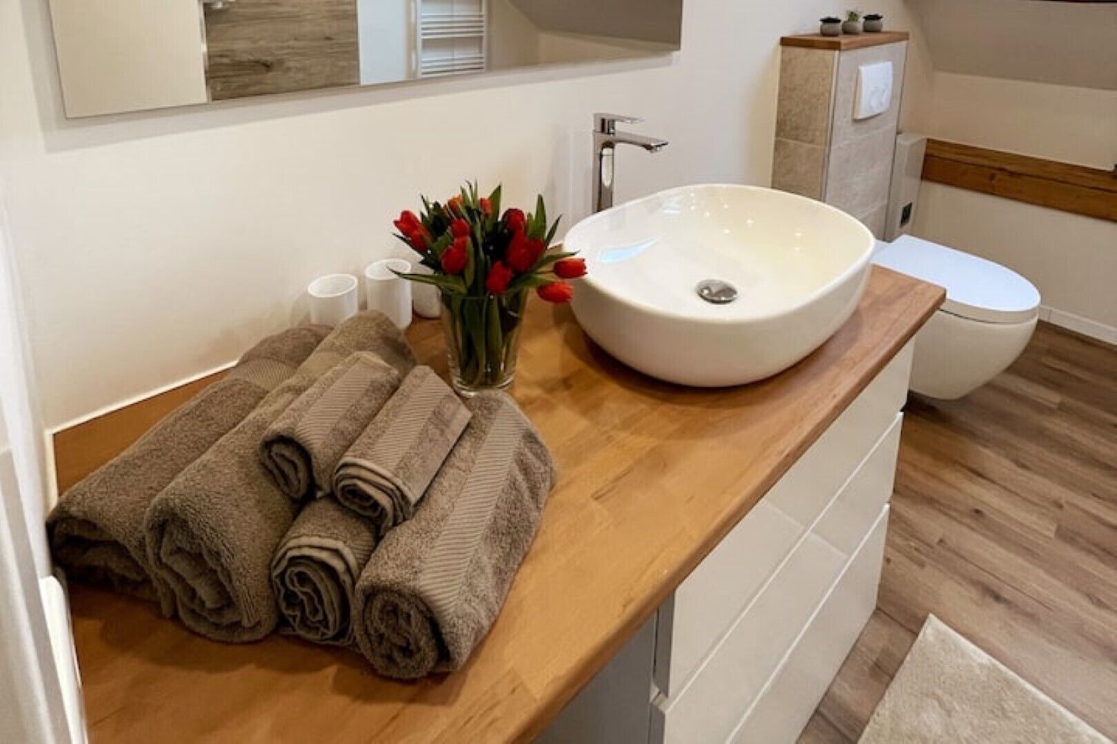 Un baño con encimera de madera, un lavabo blanco, un inodoro y un espejo.