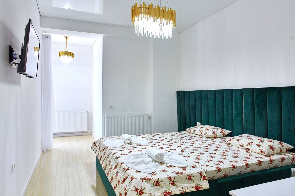 A modern bedroom with a large bed, a green headboard, and a chandelier.