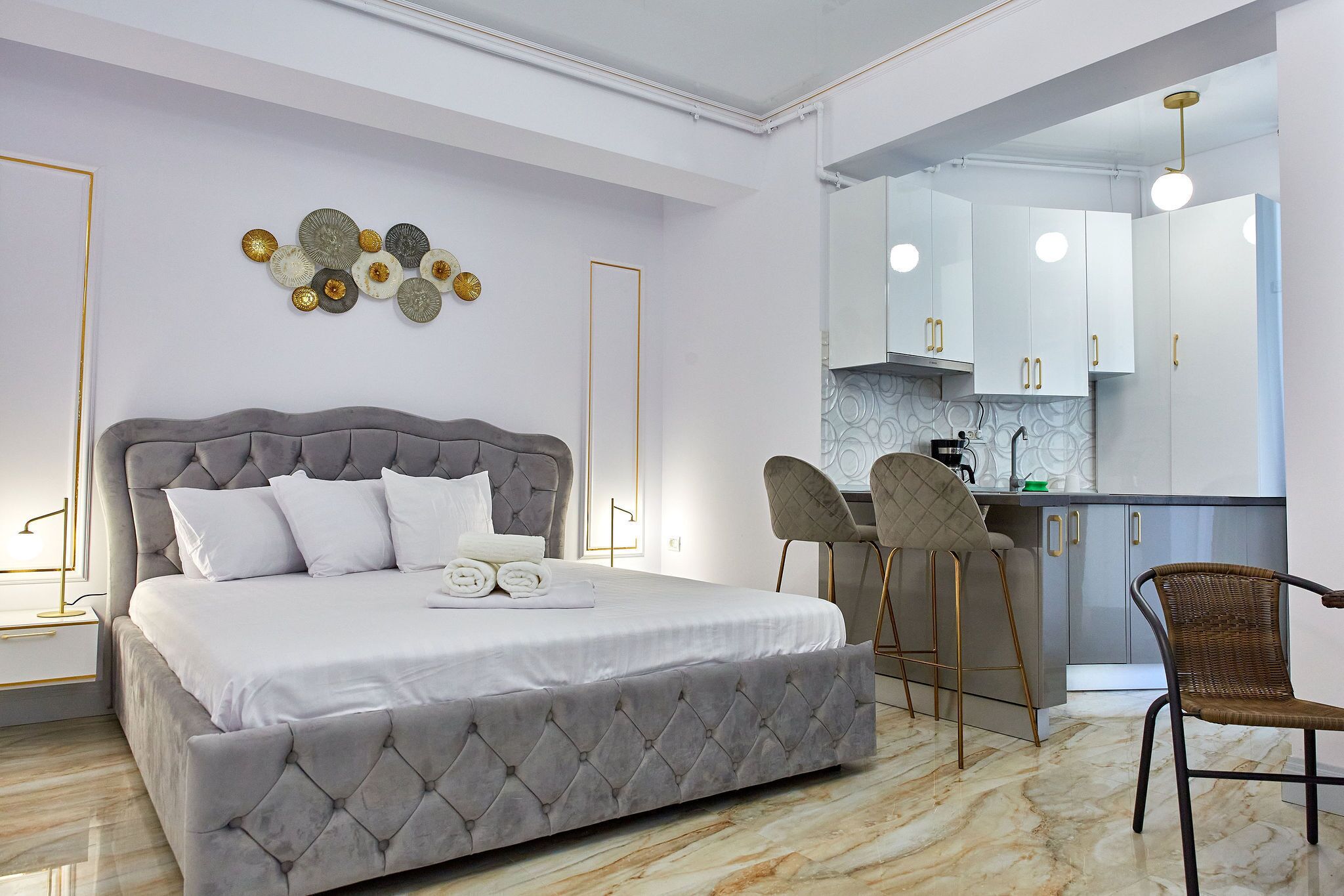 Ein modernes Schlafzimmer mit einem großen Bett, einer kleinen Küchenzeile und einem Esstisch mit Stühlen.