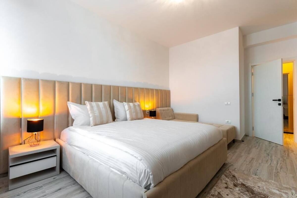 A modern hotel room with a large bed, two bedside tables with lamps, and a neutral color scheme.