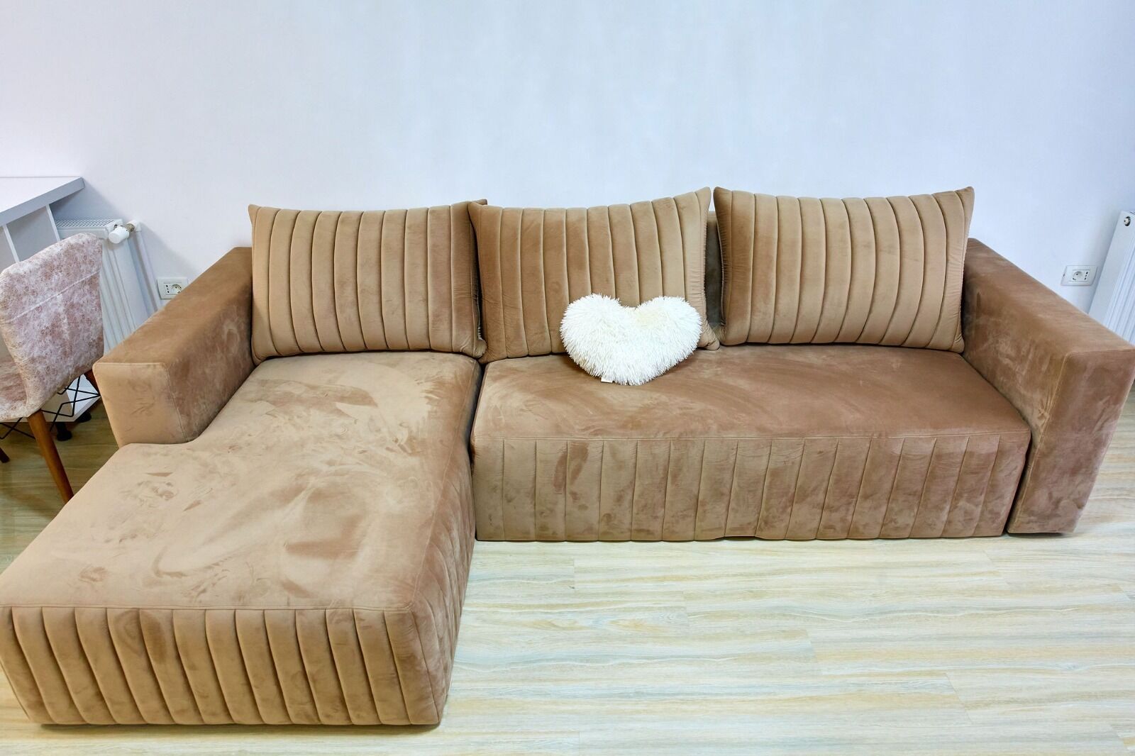 A brown sectional sofa with a heart-shaped pillow and a matching ottoman.