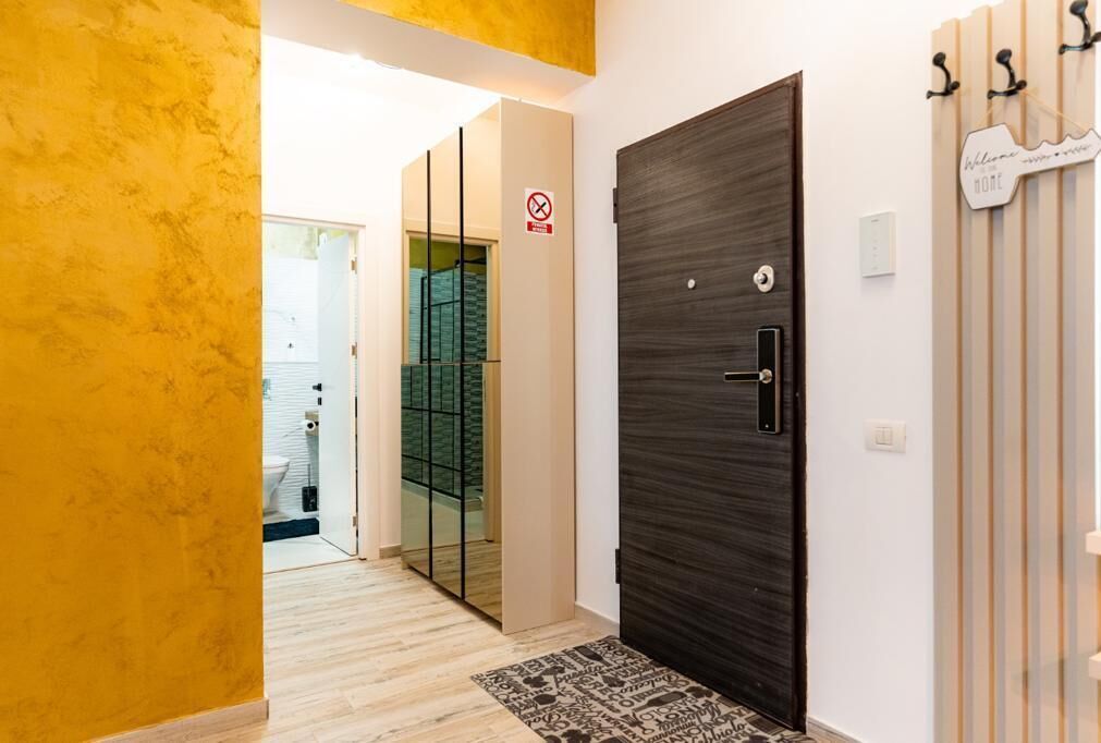 Un pasillo con una puerta de madera oscura, una pared amarilla y un adorno de pared a rayas.