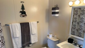 A bathroom with a toilet, sink, and towels. - The Kenai Inn (Kenai)