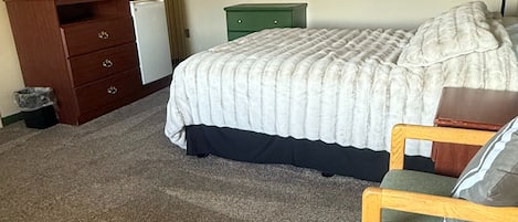 Een slaapkamer met een bed, een bureau met een computer, een stoel en een televisie aan de muur.